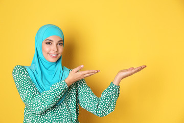 Portrait of young Muslim woman in hijab against color background. Space for text