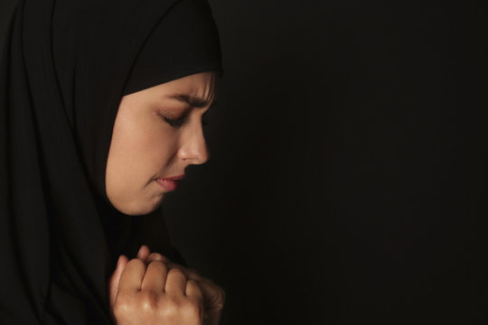 Portrait Of Sad Muslim Woman In Hijab  Praying On Dark Background. Space For Text