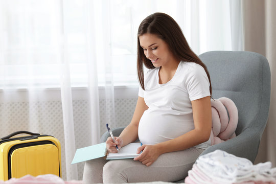 Pregnant woman writing packing list for maternity hospital at home