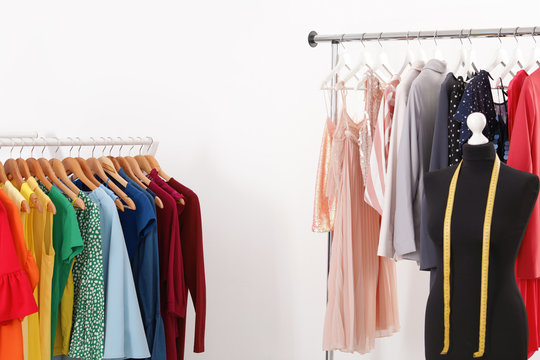 Racks with collection of trendy clothes on white background. Stylist's workplace