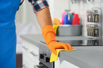 Man cleaning kitchen counter with rag, closeup