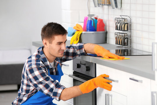Man cleaning kitchen counter with rag in house