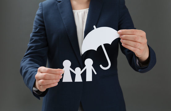 Woman holding cutout paper family and umbrella, closeup. Life insurance concept
