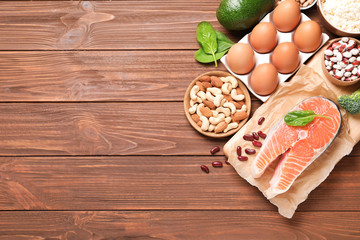 Set of natural food high in protein and space for text on wooden background, top view