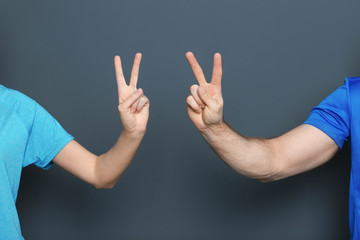 Man and woman showing victory gestures on color background