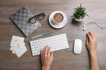 Woman using computer mouse and keyboard at office table, top view