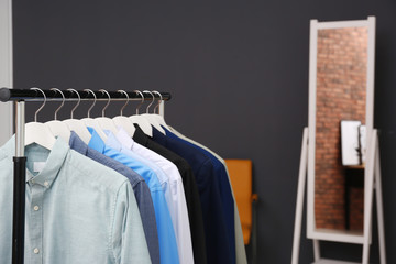 Wardrobe rack with stylish clothes in dressing room. Space for text