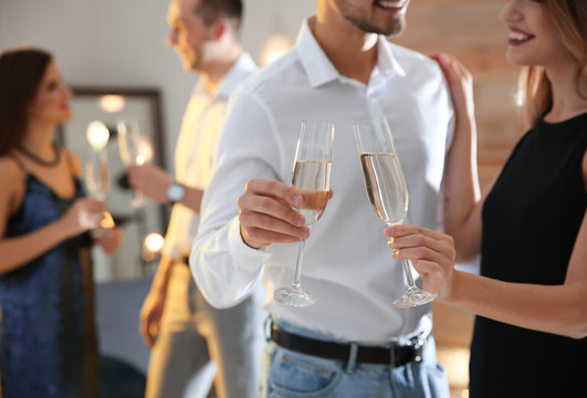 Couple clinking glasses with champagne at party indoors, closeup