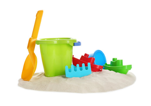 Plastic beach toys on pile of sand against white background