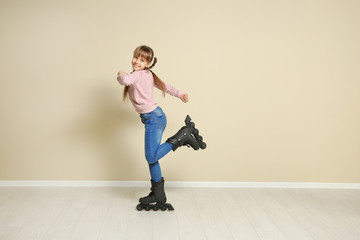 Fototapeta na wymiar Cute girl with inline roller skates near color wall