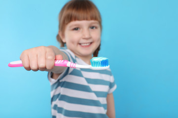 Little girl with toothbrush on color background. Teeth care