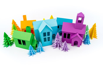 Rainbow house glued out of paper stands in the multicolored forest.