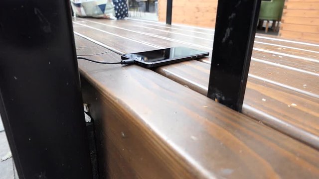 A person using a street charging station for his phone.
