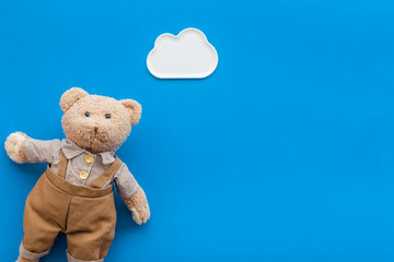 Toys for newborn baby set with teddy bear and clouds on blue background flat lay space for text