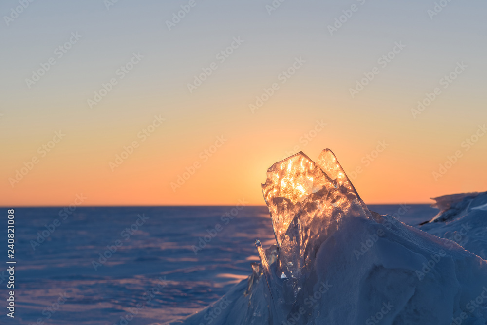 Wall mural transparent fragments of ice against the backdrop of the endless snowy landscape during sunset.