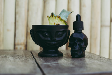 Tiki glass and skull on the bamboo wall background