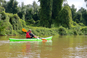 Man paddle green kayak on summer Danube river. Summer kayaking. Concept for adventure, travel, action, lifestyle