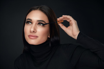 Obraz premium Makeup Cosmetics. Woman With Beauty Face Applying Black Mascara