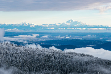 view of downtown covered in cloud from snow covered mountain with snow covered mountain range at...