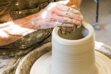      Artist potter in the workshop creating a ceramic vase. Hands closeup. Twisted potter's wheel....