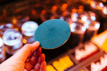 Green circle coaster paper holding with left hand with blur background. © artitwpd