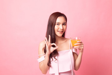 Young Asian woman show OK  with orange juice