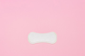 Feminine hygiene pad on a pink background. Concept of feminine hygiene during menstruation. Flat lay, top view