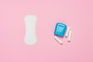 Feminine hygiene tampons, box for shipping and storage and sanitary pad on a pink background. Concept of feminine hygiene during menstruation, choice between pads and tampons. Flat lay, top view