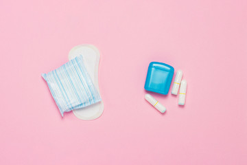 Feminine hygiene tampons, box for shipping and storage and sanitary pad on a pink background. Concept of feminine hygiene during menstruation, choice between pads and tampons. Flat lay, top view