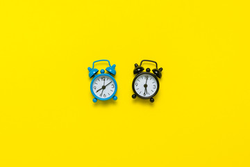 Blue and yellow alarm clocks on a yellow background. Concept day and night, time management,...