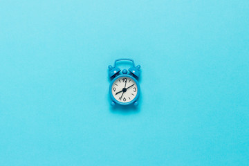 Blue alarm clock on a blue background. Concept day and night, time management, planning, schedule of day and night, minimalism. Flat lay, top view