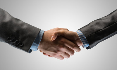 Business handshake as idea for unity and cooperation or greeting. Mixed media