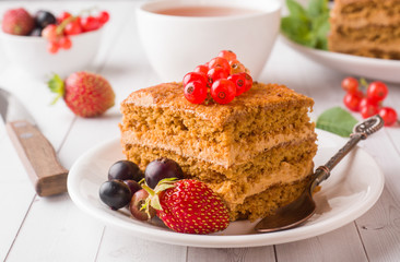 Honey cake with strawberries, mint and currant, a Cup of tea on a light background
