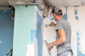 Using equipment for plaster walls. Rear back behind view photo of unrecognizable handyman master...