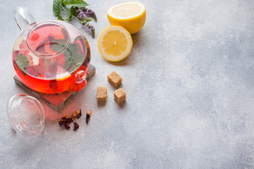 Glass teapot with tea, mint and lemon on grey table with copy space