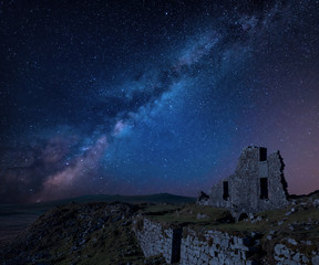 Stunning vibrant Milky Way composite image over abandoned Foggintor Quarry in Dartmoor with raking soft sunlight over ruins and derelict buildings