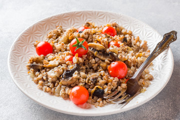 Buckwheat porridge with mushrooms and cherry tomatoes on a plate.