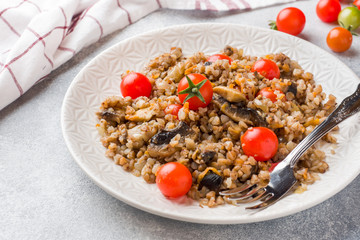Buckwheat porridge with mushrooms and cherry tomatoes on a plate.