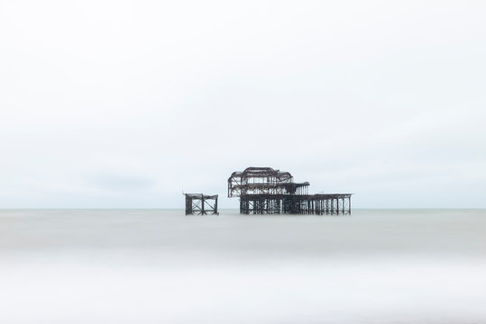 Landscape image of derelict Victorian West Pier at Brighton in West Sussex with dramatic evening sky