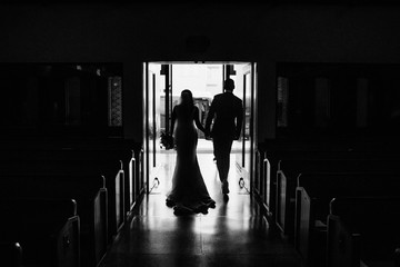 bride and groom walking down church aisle after ceremony in black and white