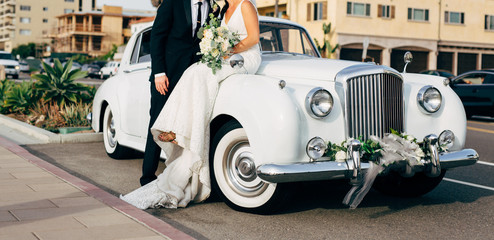 bride and groom next to classic car on street kissing