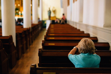 senior woman praying at a pew in church
