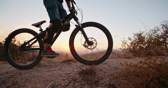 Mountain cycler riding up the path in mountains in sunset, following the trail or road - extreme, fitness, 4k