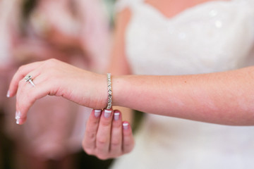 bride putting on bracelet for wedding ceremony