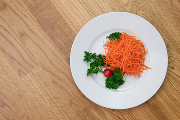 Ground carrot on white plate with parsley and mini tomatoes