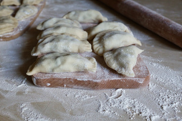 Raw traditional vareniki, dumplings, pierogi top view on a wooden board