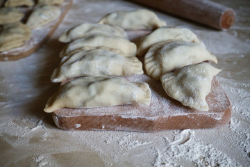 Raw traditional vareniki, dumplings, pierogi top view on a wooden board