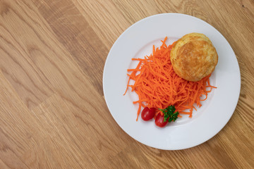 Ground carrot with egg bun and tomatoes laying on a plate with parsley on wooden table