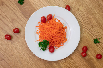 Ground carrots, tomatoes and parsley on white plate and items all over the table
