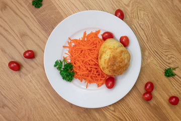 Ground carrots, egg bun, tomatoes and parsley on white plate and items all over the table